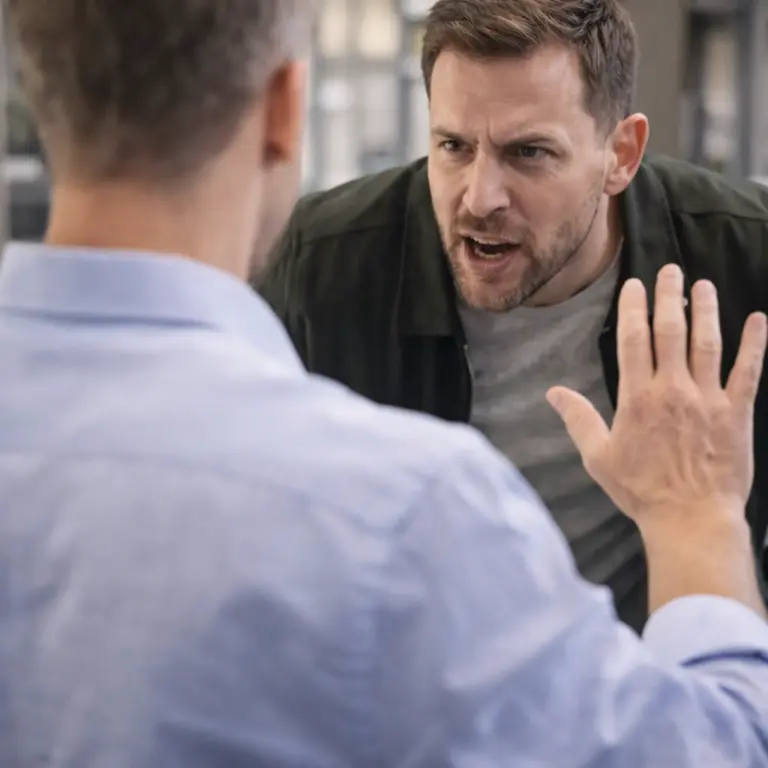 Man responding calmly to an aggressive person by keeping distance and raising his hand in a de-escalating gesture