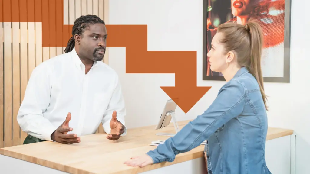 Two people having a serious conversation across a desk in an office while discussing a problem or situation.
