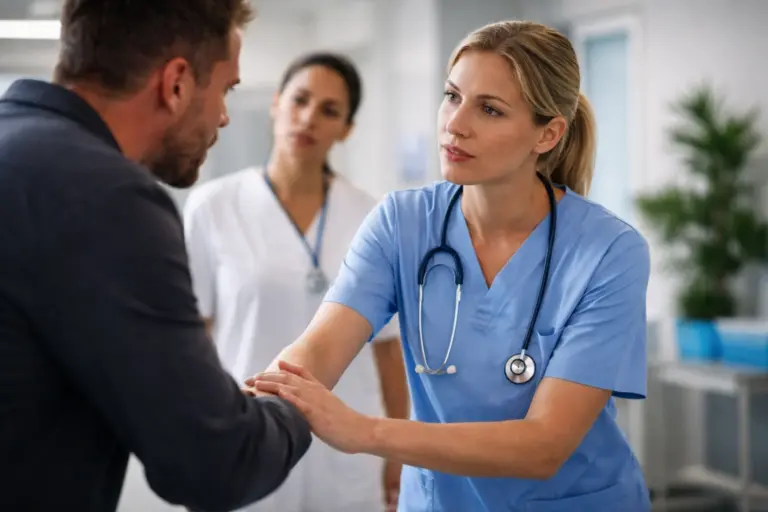 Zorgprofessional in blauwe medische kleding stelt een patiënt gerust tijdens een gesprek in een klinische omgeving.